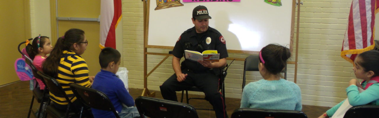 Photo: A police officer reading a book to children